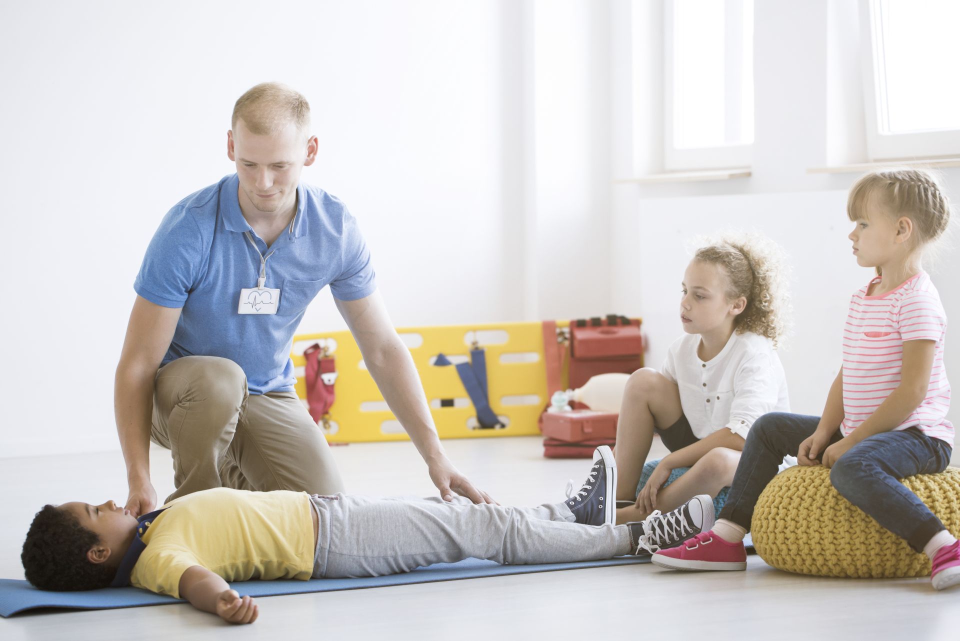 Pfleger übt im Beisein von Kindern an einem anderen Kind die Reanimation bzw. erste Hilfe